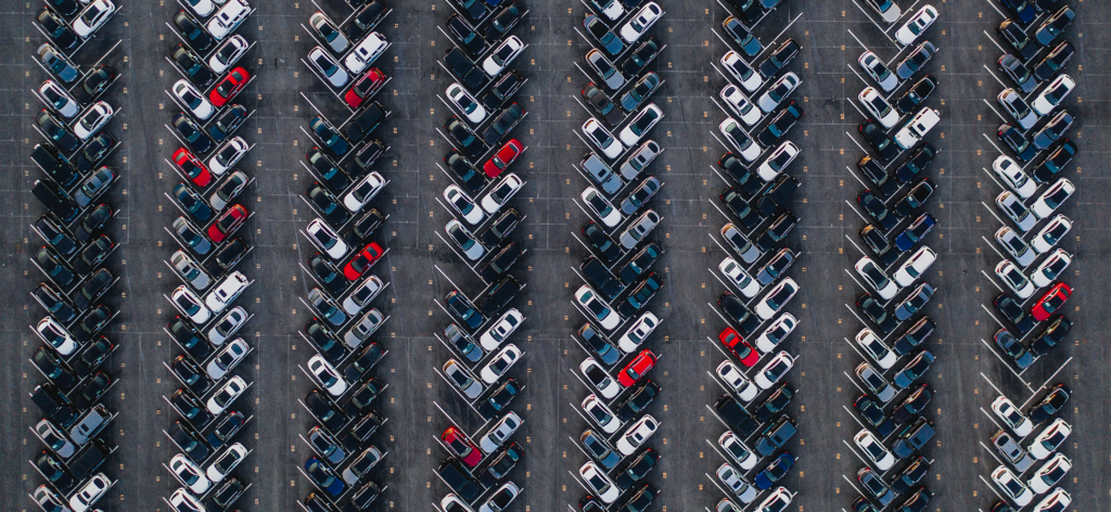 Aerial photograph of cards parked diagonally in rows in a parking lot.